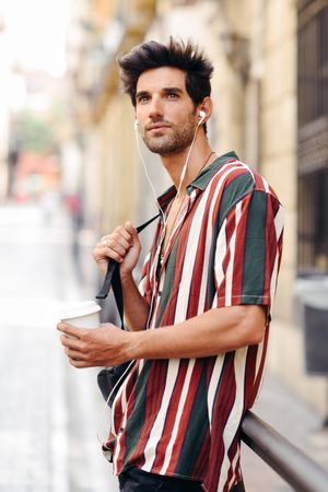 Male in striped shirt standing in the streets of Granada, Spain with coffee