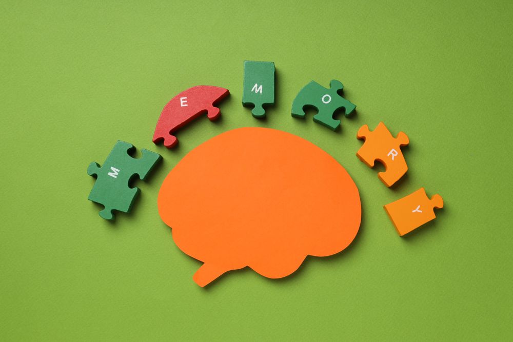 Paper cut out of brain with puzzle pieces on green background