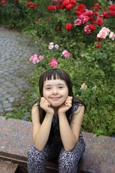 Beautiful girl with bangs sitting near a garden
