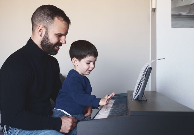 Father teaching son to play piano
