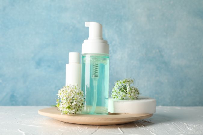 Lotion, allium flowers, sponge and cream on blank background, copy space