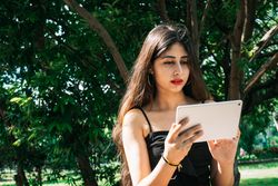 Woman holding tablet computer near trees