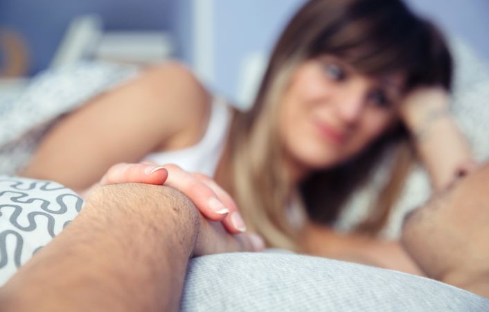 Selective focus of woman looking affectionately at man lying on bed