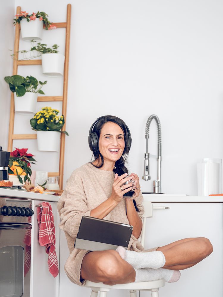 Female in headphones using tablet while relaxing with coffee