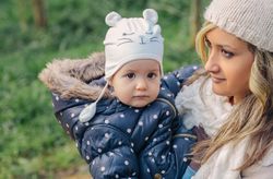 Mother holding daughter in hat outside