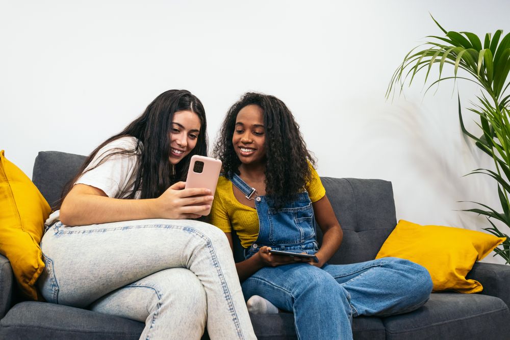 Modern lifestyle: Two young women using mobile devices at home