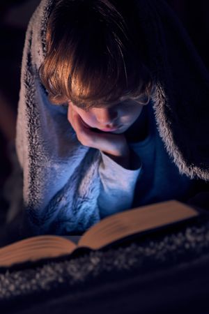 Boy reading book in darkness
