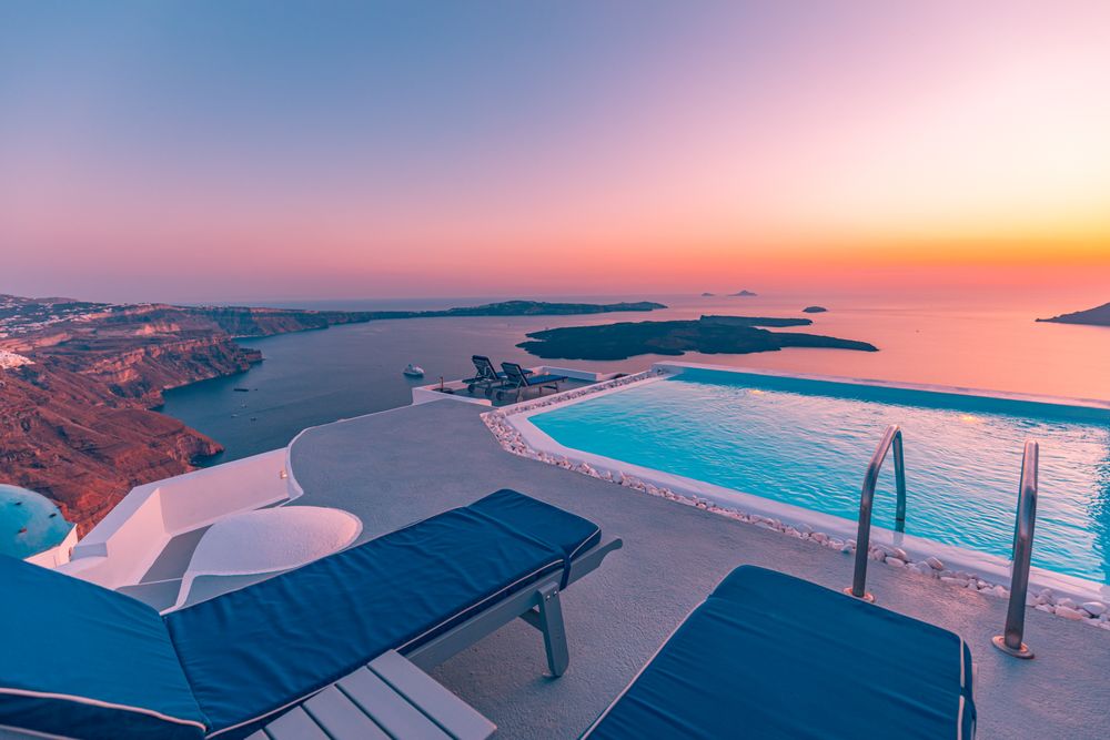 Pool with lounge chairs with sunset sky