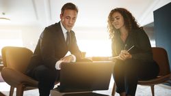 Man and woman dressed in business casual focused on a laptop