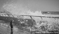 Back view of child standing against splashing sea waves 5kwBG5