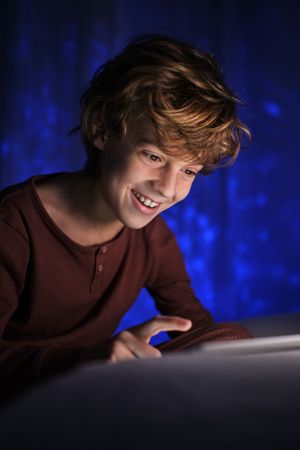 Smiling boy using tablet in dark room