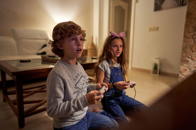 Perplexed children with gaming station sitting at living room