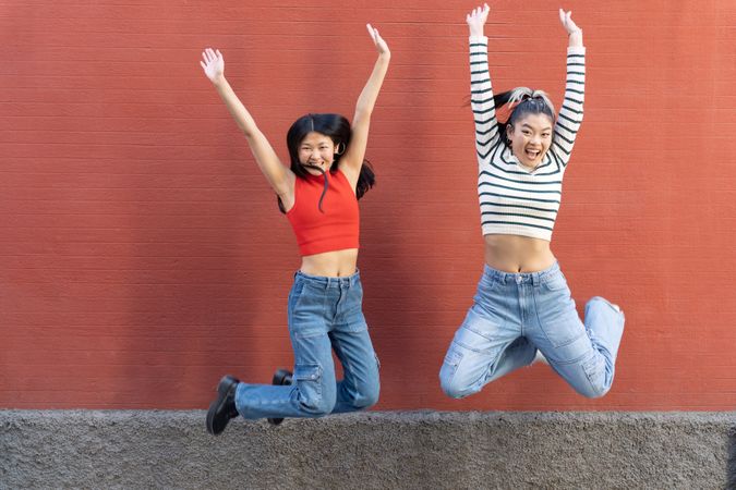 Two woman in jeans jumping for joy