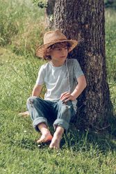 Thoughtful boy relaxing on grass near tree