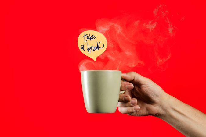 Hand holding a steaming coffee mug with "take a break" message on red background.