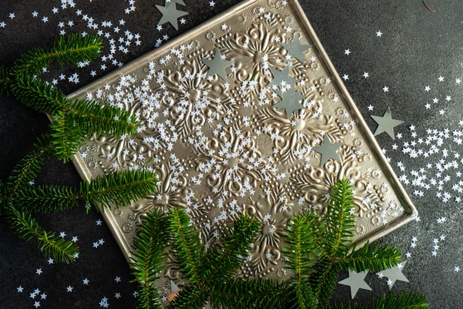 Christmas card concept of pine branches and star confetti on silver tray