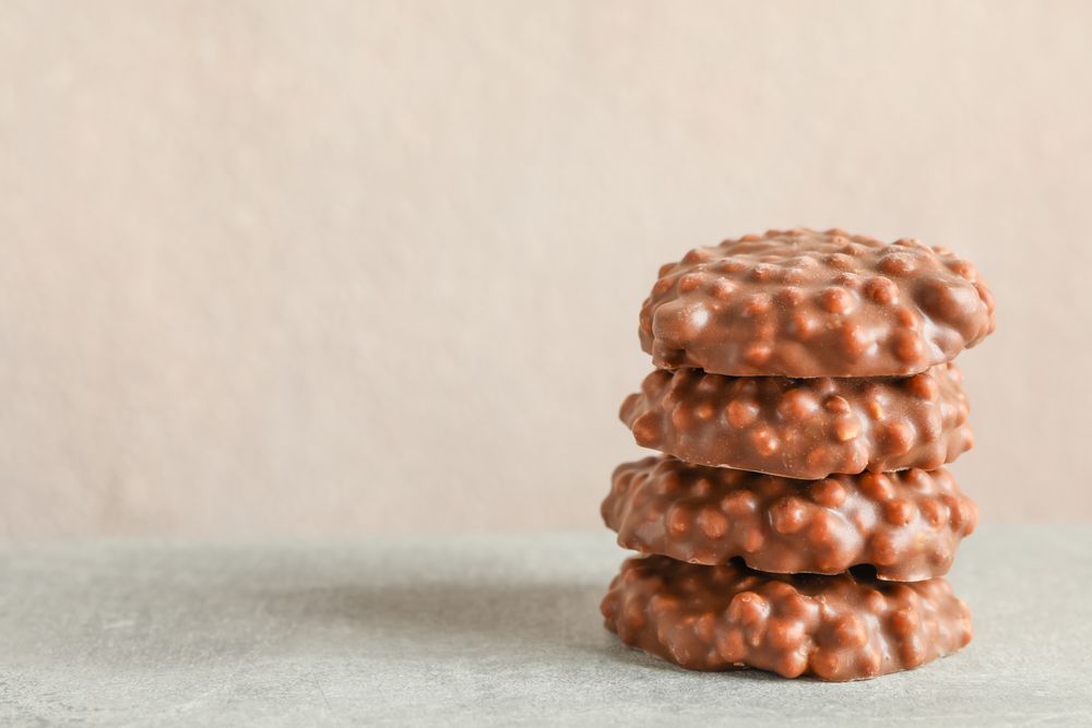 Stack of chocolate cookies on grey table against light background, space for text