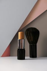Concealer stick and make up brush on modern background