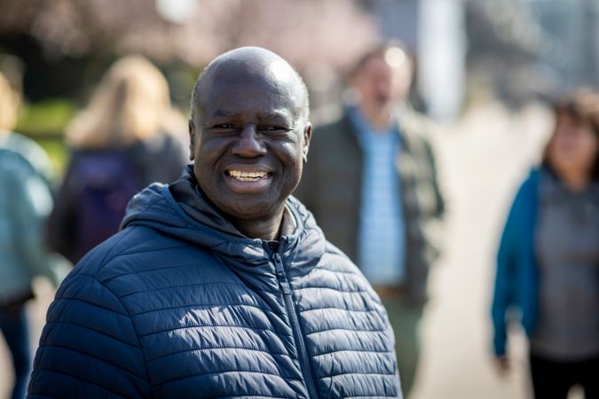 Smiling man walking by the river with people behind him