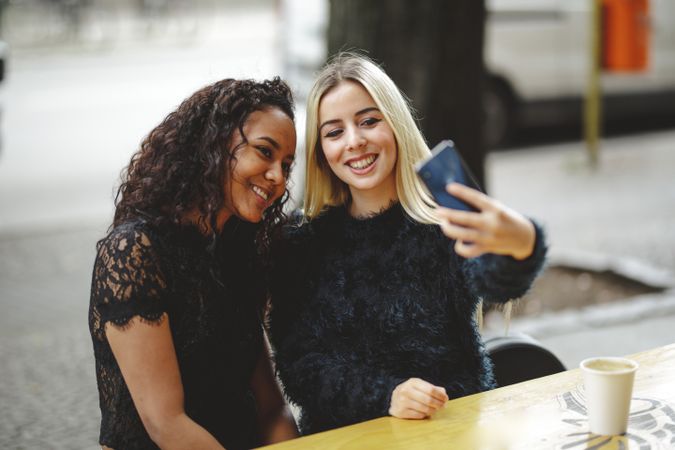 Friends taking selfie in street cafe