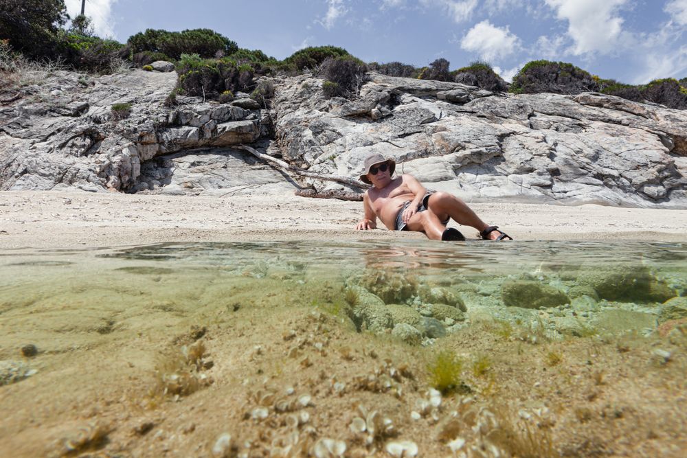 Man lying on sandy shore near water