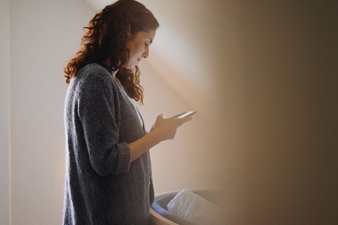 New mom using smart phone before baby wakes up for feeding