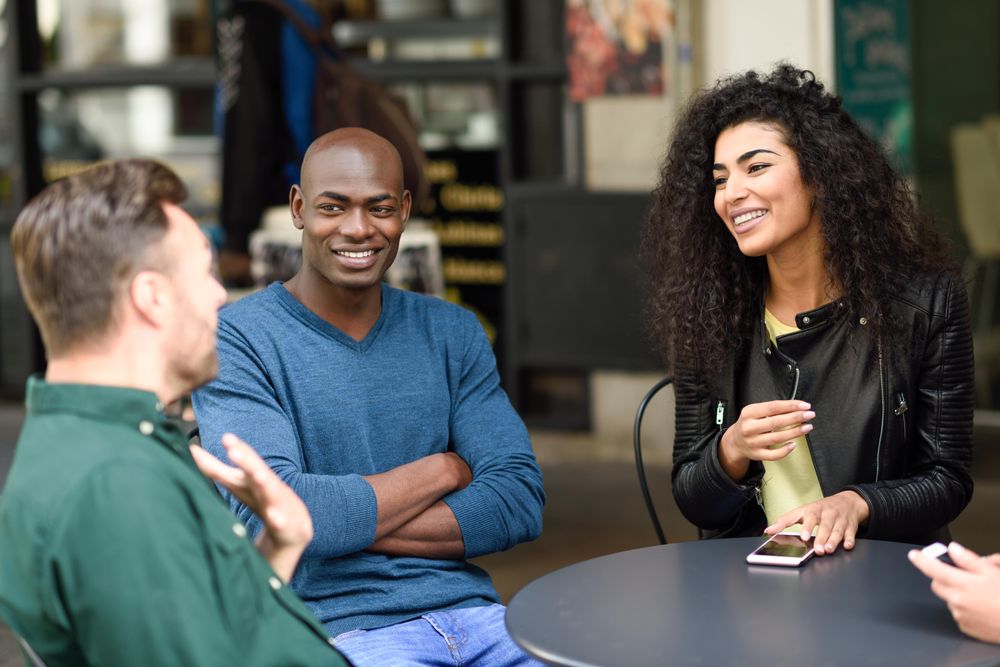 Three friends relaxing at cafe table outside