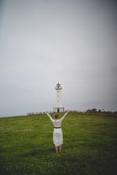 Woman walking in green meadow near lighthouse