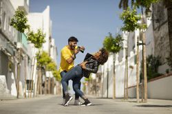 Excited man taking photo of bending girlfriend