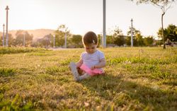 Happy baby girl playing sitting on a grass park