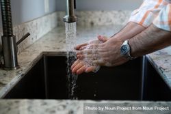 Man’s hands washing with soap in the sink 0PjXl4
