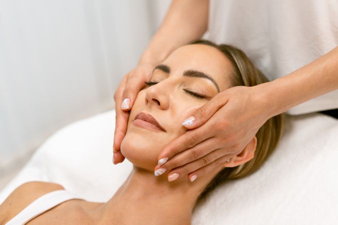 Woman having her face massaged by therapist