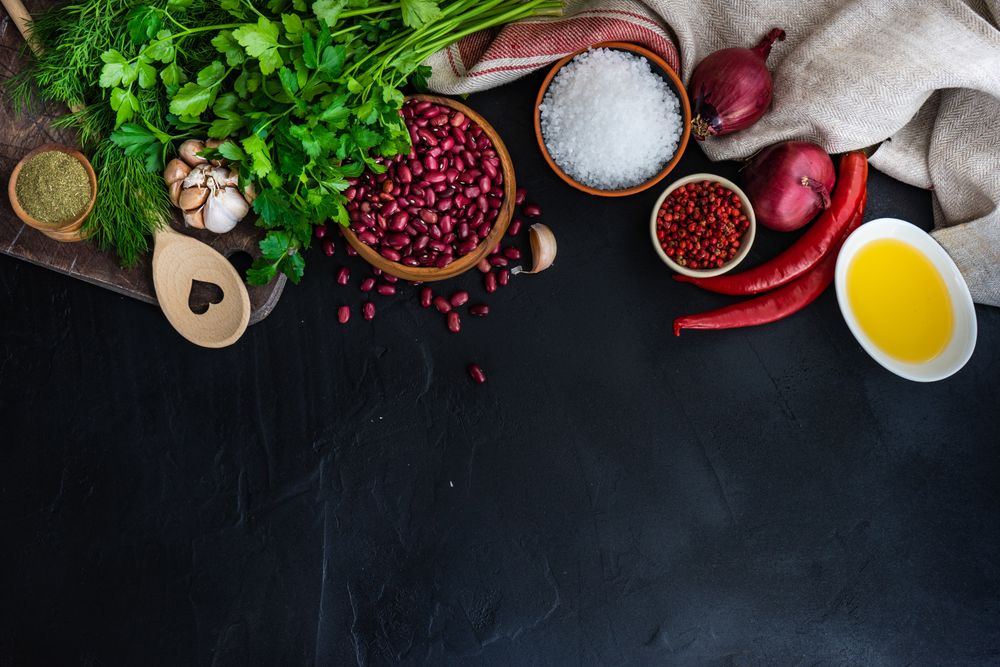 Counter of kitchen with bowl of dried kidney beans, herbs and seasoning with copy space