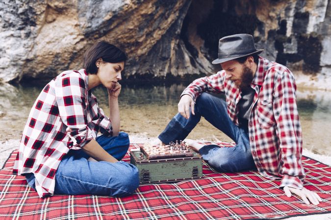 Casual couple playing chess on shore