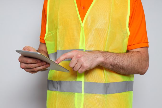 Young man civil engineer with tablet on light gray background