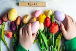 Flat lay of hands reaching for tulips and egg decorations