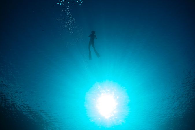 Unrecognizable boy diving in blue sea