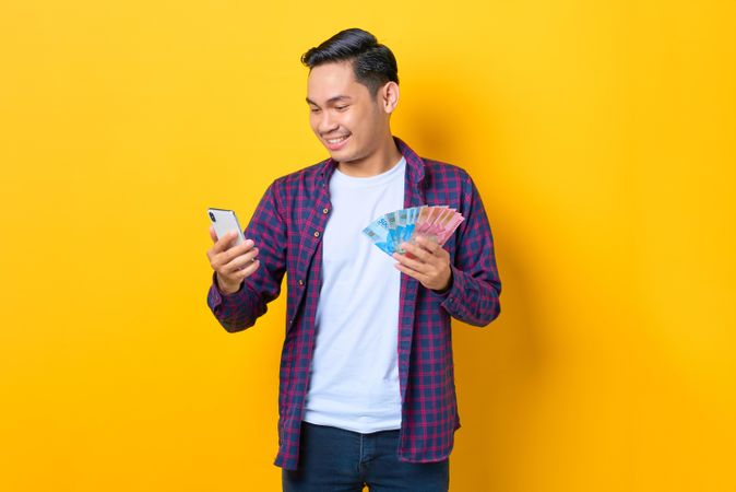 Man looking at with smart phone and holding cash