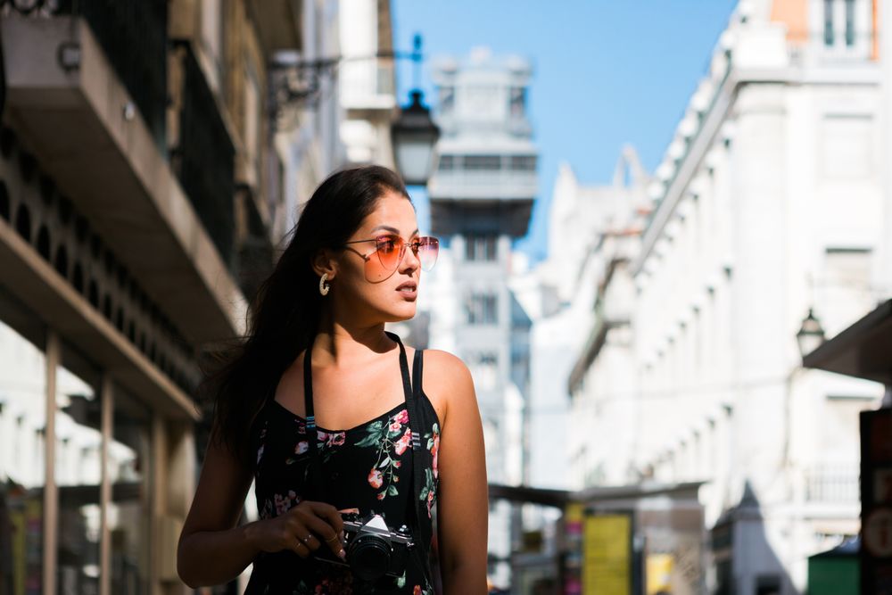 Woman holding a camera while standing on street