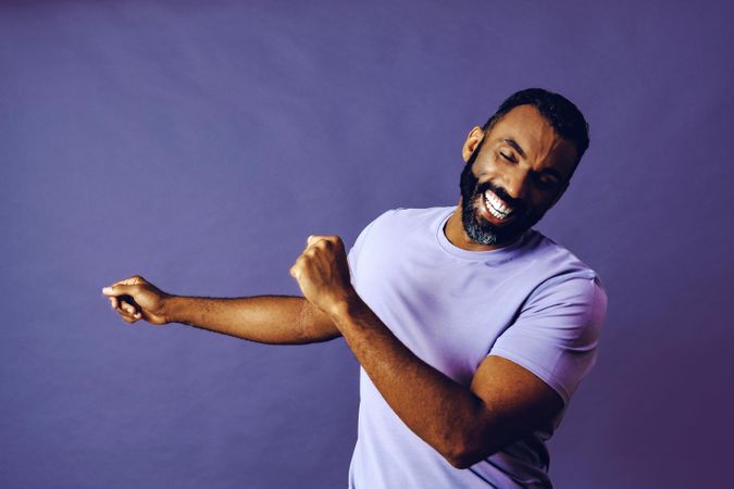 Smiling male in purple studio with hands to the side, copy space