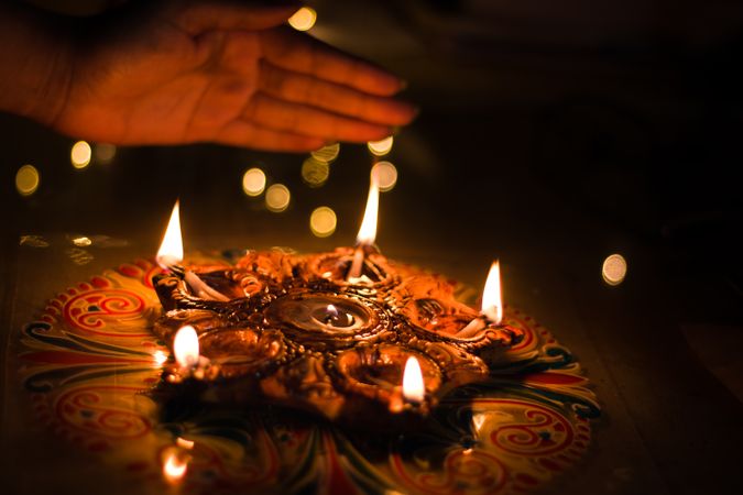 Cropped image of a hand above a rangoli style diyas during Diwali festival