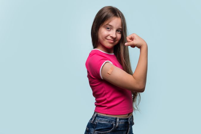 Girl flexing arm with bandage after vaccination