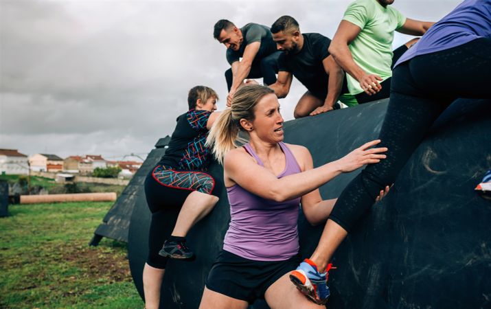 Participants in an obstacle course climbing a drum