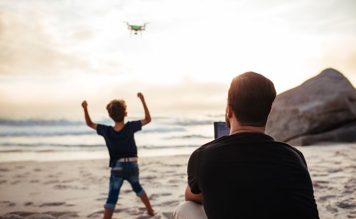 Father flying drone with child cheering him on