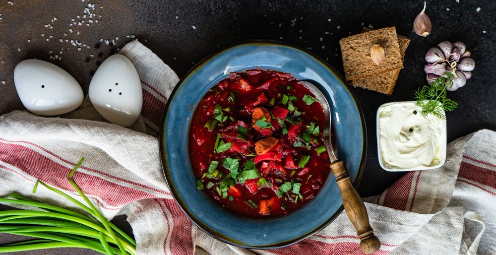 Top view of Ukrainian beetroot soup borscht on counter served with cracker and sour cream