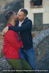 Two men kissing each other near stone wall outside 4dv9l0