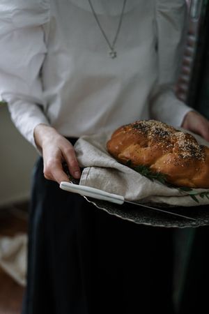 Cropped image of woman holding a silver tray with bread