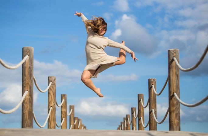 Woman with textile posing in air on footbridge