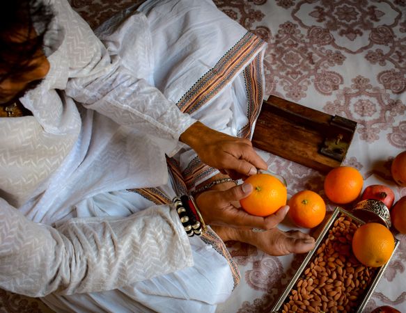 Top view of a man sitting on floor eating an orange