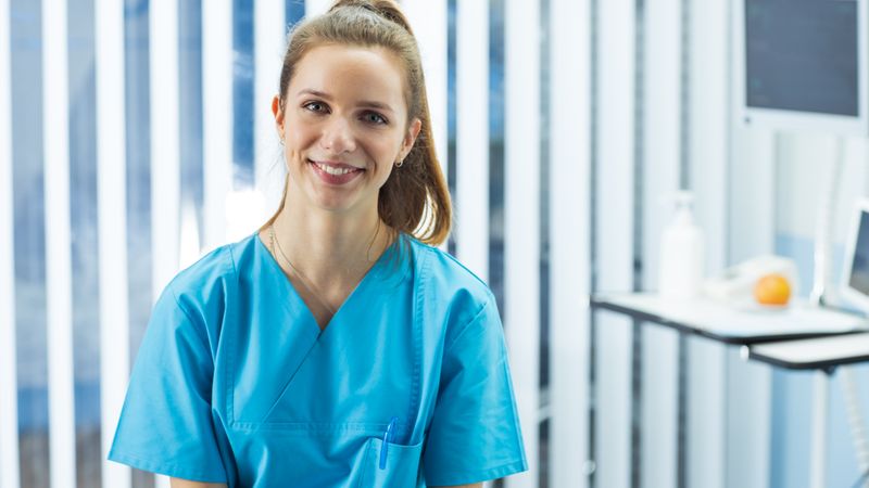 Portrait Shot of Beautiful Young Nurse Charmingly Smiles at the Camera